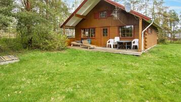 A wooden cabin with a porch, outdoor seating, and a chimney.