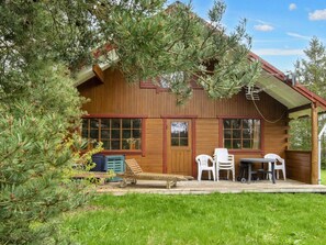 Een houten vakantiehuisje met een veranda, een tafel en stoelen.