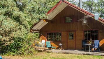 A wooden cabin with a porch, outdoor seating, and a satellite dish.