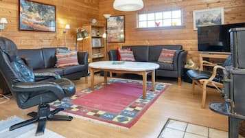 A cozy cabin interior with a sofa, chairs, a table, and a fireplace.