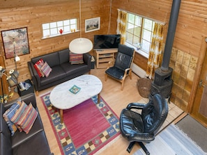 L’intérieur d’un chalet accueillant, avec un canapé, un fauteuil, une télévision et une cheminée.