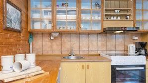 A wooden cabin kitchen with a sink, stove, and cabinets. - 6 Person Holiday Home in Orsted (Ørsted)