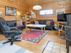 A cozy cabin interior with a sofa, chairs, a table, and a fireplace.