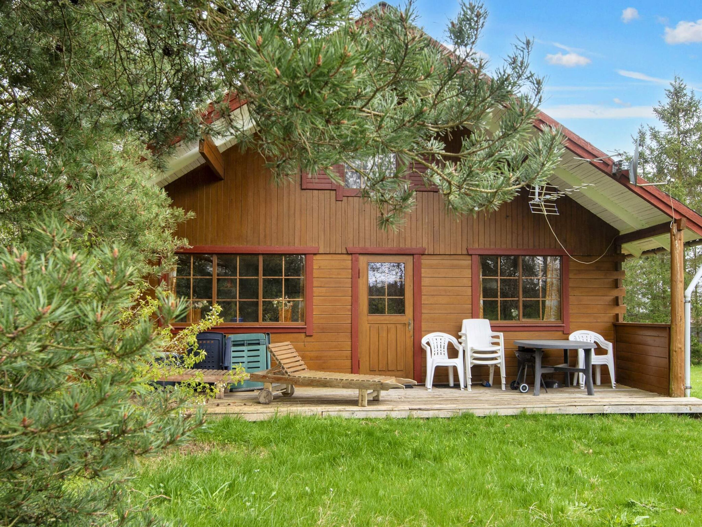 A wooden cabin with a porch, a table, and chairs.