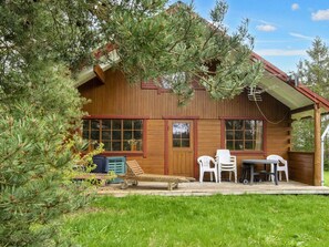 Een houten blokhut met een veranda, een tafel en stoelen.