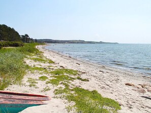 A beach with a sandy shore, a boat, and a calm sea.