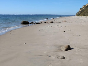 A sandy beach with scattered rocks and a clear view of the ocean.