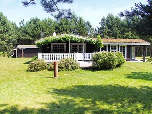 A house with a porch, a small garden, and a shed in the background.