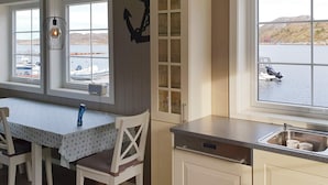 A kitchen with a view of a lake, a dining area with a table and chairs, and a hanging light fixture. - 4 Star Holiday Home in Oksvoll (Orland)