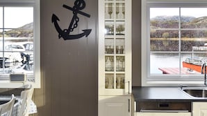 A kitchen with a large window, a wooden door, and a view of boats on the water. - 4 Star Holiday Home in Oksvoll (Orland)