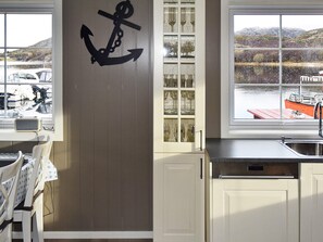 A kitchen with a large window, a wooden door, and a view of boats on the water. - 4 Star Holiday Home in Oksvoll (Orland)