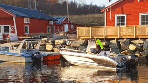 A marina with boats docked, a red building with a balcony, and a hill in the background. - 4 Star Holiday Home in Oksvoll (Orland)