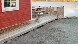 A red building with a wooden deck and picnic tables by a calm lake. - 4 Star Holiday Home in Oksvoll (Orland)