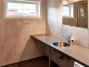 A bathroom with a sink, mirror, and window.