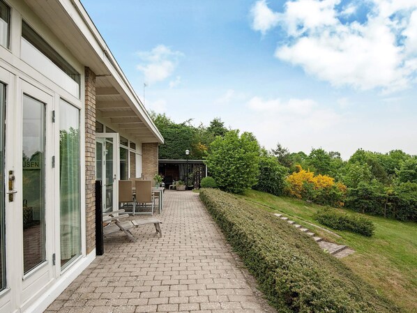 A modern building with a paved walkway leading to a covered outdoor seating area.