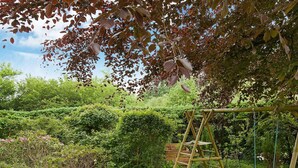 A wooden swing set in a lush garden with dense foliage and a variety of plants. - Tranquil Holiday Home in Ebeltoft near Sea (Ebeltoft)