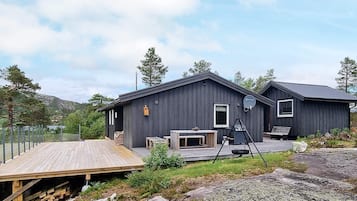 A modern cabin with a deck, a fireplace, and a satellite dish.