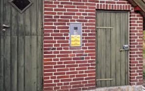 A brick wall with two wooden doors, one of which has a sign attached.