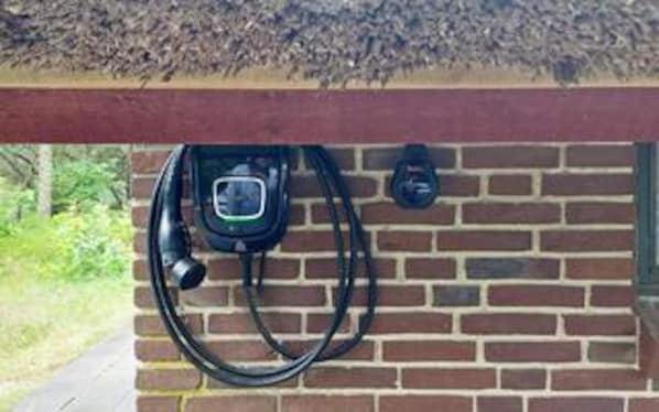 A brick wall with a power outlet and a cable.