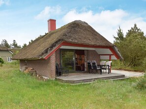 A thatched-roof house with a brick exterior, a chimney, and a patio with outdoor seating. - 6 Person Holiday Home in Norre Nebel (Norre Nebel)