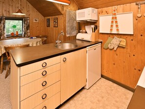 Cocina compacta con armarios de madera, un lavamanos, un microondas y un refrigerador pequeño.