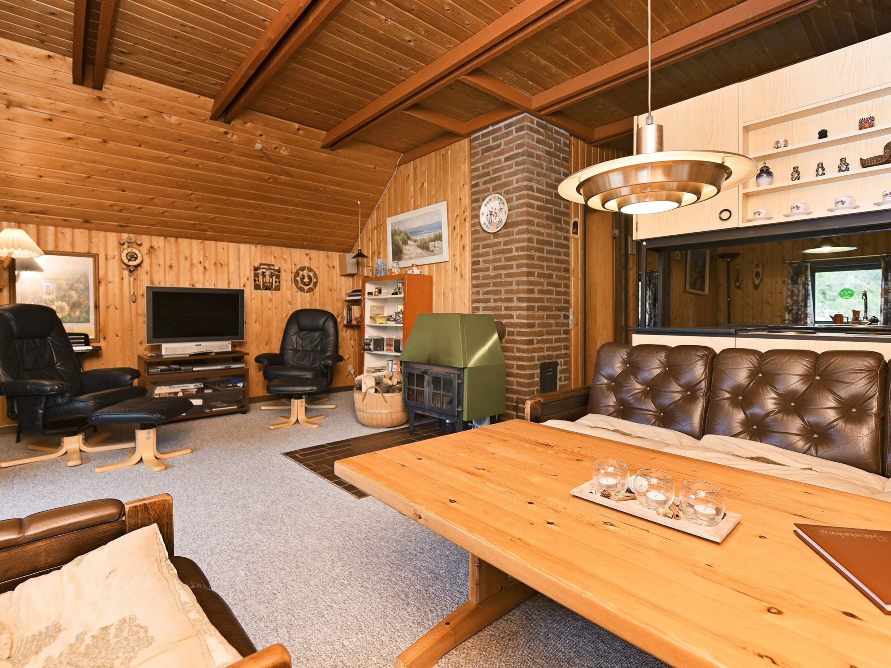 A cozy living room with a fireplace, leather seating, a dining table, and a television.