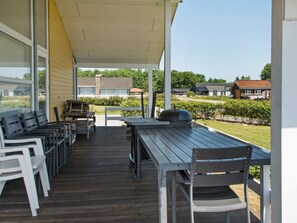 A covered outdoor area with a table and chairs, a barbecue grill, and a view of residential buildings. - 5 Star Holiday Home in Sydals (Sydals)