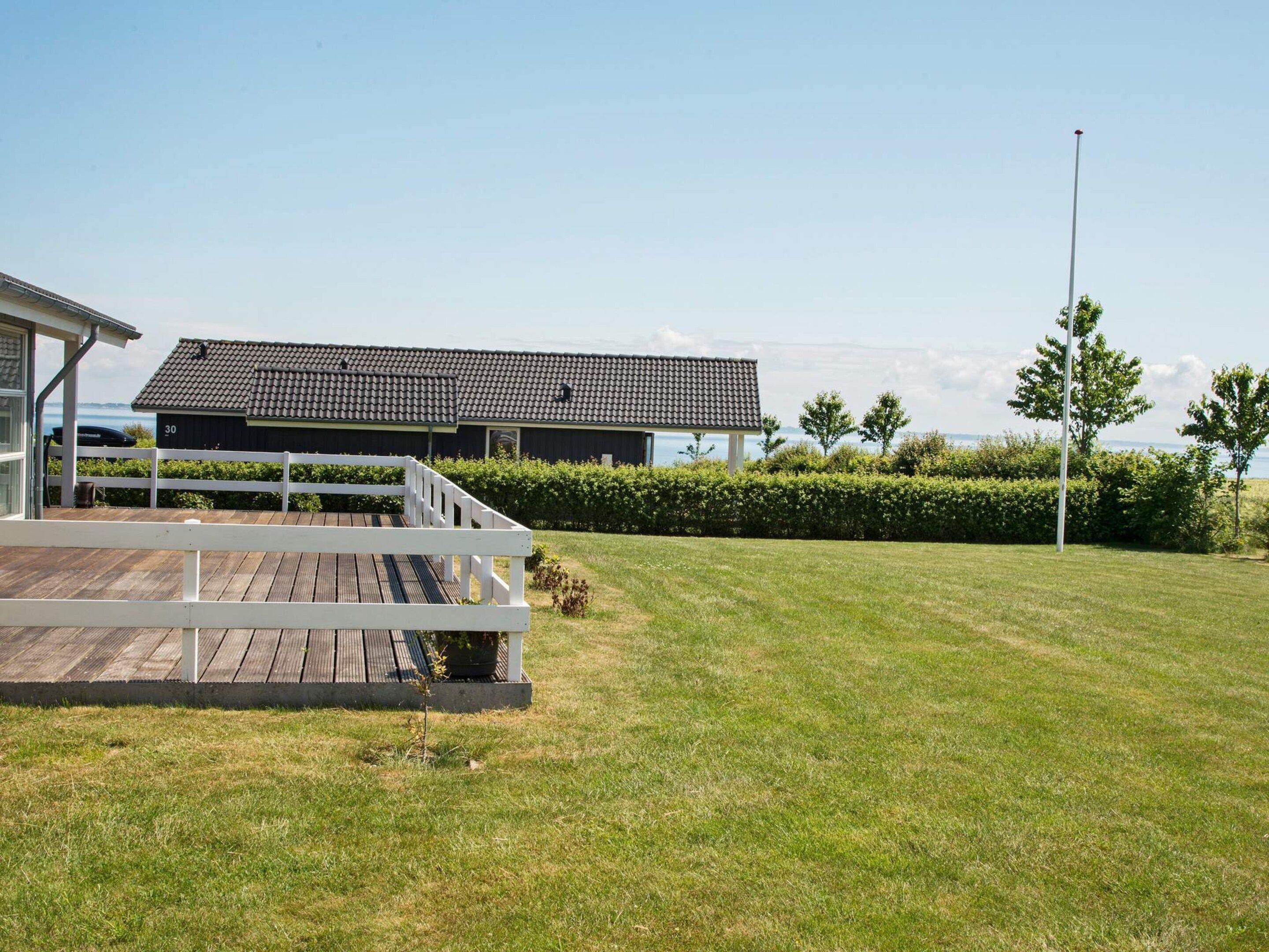 A building with a tiled roof, a wooden deck, and a grassy lawn.