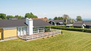 Ett bostadsområde med moderna hus, en grön gräsmatta och fri utsikt över havet.