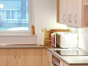 Une cuisine avec des meubles de rangement en bois, une fenêtre et un four à micro-ondes.