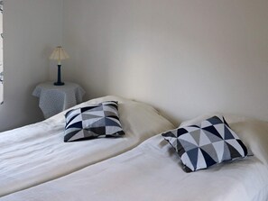A bedroom with two beds, each with a pillow featuring a geometric pattern. There is a small round table with a lamp beside one of the beds. - 2 Person Holiday Home in Falkenberg (Falkenberg)