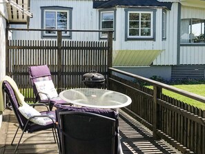 A deck with a glass-top table, two chairs, and a barbecue grill. - 2 Person Holiday Home in Falkenberg (Falkenberg)