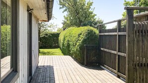 A wooden deck leading to a house with a white exterior and a black fence.