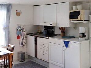 A compact kitchen with white cabinets, a coffee maker, and a microwave on the countertop. - 2 Person Holiday Home in Falkenberg (Falkenberg)