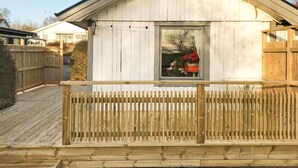 A wooden structure with a balcony, a window with a view of flowers, and a clear sky.
