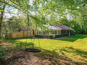 Une maison avec une véranda, une balançoire et un espace couvert donnant sur la cour.