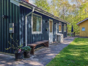 A row of cabins with a covered outdoor seating area, a small table, and potted plants.