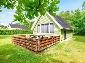 A single-story house with a green exterior, a wooden deck, and a picnic table. - 5 Person Holiday Home in Grindsted (Grindsted)