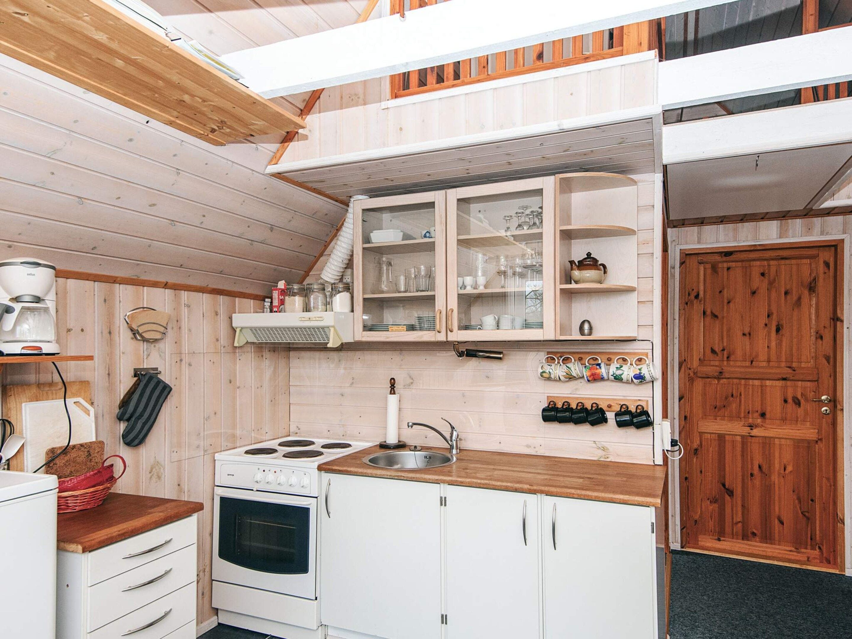 A compact kitchen with white cabinetry, a stove, and a sink.