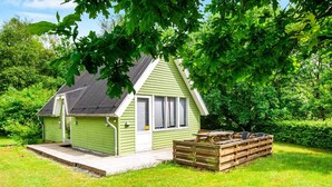 A small, single-story house with a sloped roof, a front porch, and a wooden deck. - 5 Person Holiday Home in Grindsted (Grindsted)