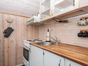 A compact kitchen with a wooden countertop, a stove, a sink, and cabinets.