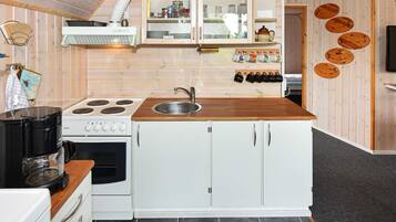 A compact kitchen with a stove, sink, and white cabinets.