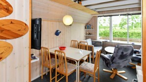 A dining area with a table and chairs, a television, and a view of greenery outside. - 5 Person Holiday Home in Grindsted (Grindsted)