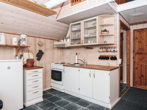 A compact kitchen with white cabinets, a stove, and a coffee maker. - 5 Person Holiday Home in Grindsted (Grindsted)