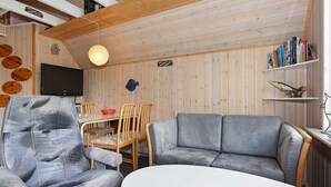 A cozy room with a grey sofa, a round table, a television, and a bookshelf with books and a fish decoration. - 5 Person Holiday Home in Grindsted (Grindsted)