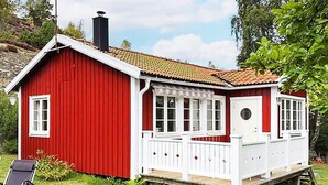 A red wooden house with a white porch and a chimney.