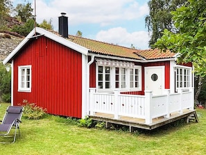 A red wooden house with a white porch and a chimney.