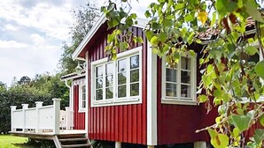 A red wooden house with a white porch and steps leading to the entrance.