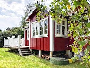 A red wooden house with a white porch and steps leading to the entrance.