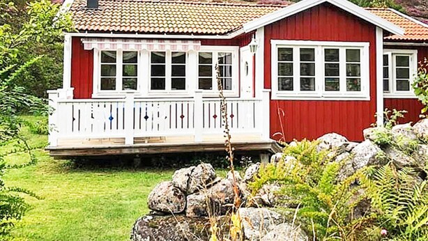 A red wooden house with a white porch and multiple windows.